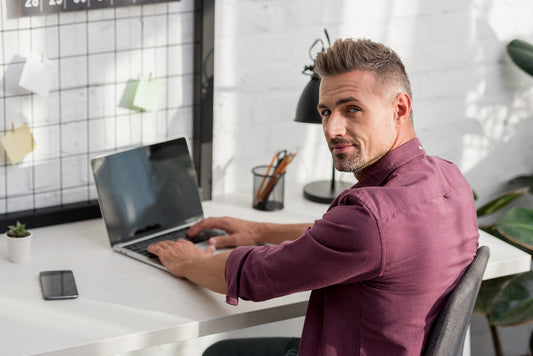 Man sitting at a desk using a laptop in a modern office setting