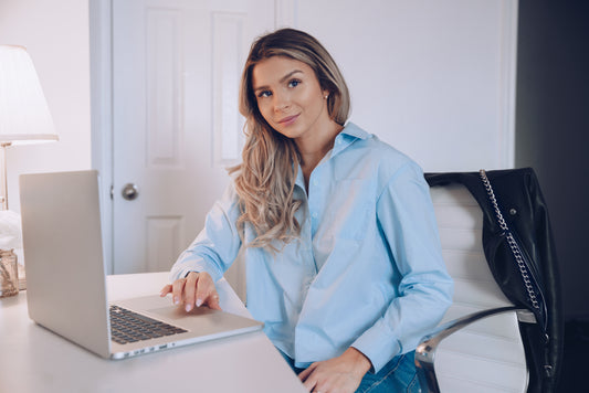 Woman in a light blue shirt using a laptop in a modern office setting